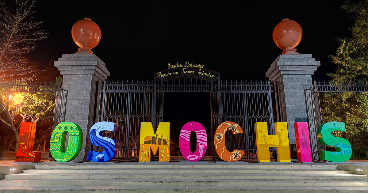 Letras coloridas de “Los Mochis” frente a la entrada del Jardín Botánico Benjamin Francis Johnston iluminadas de noche.