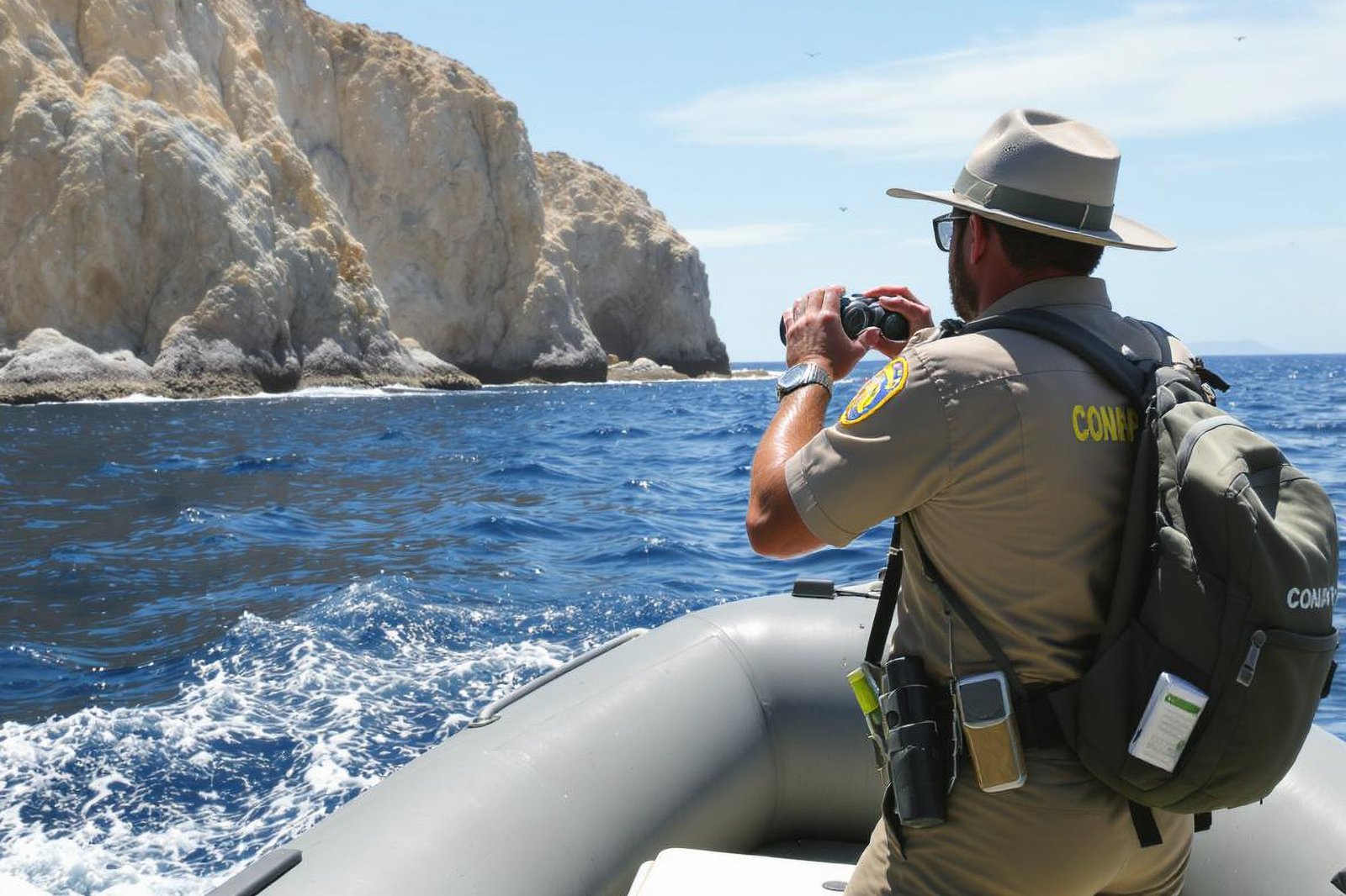 Personal de conservación observa el islote desde una lancha en patrullaje.