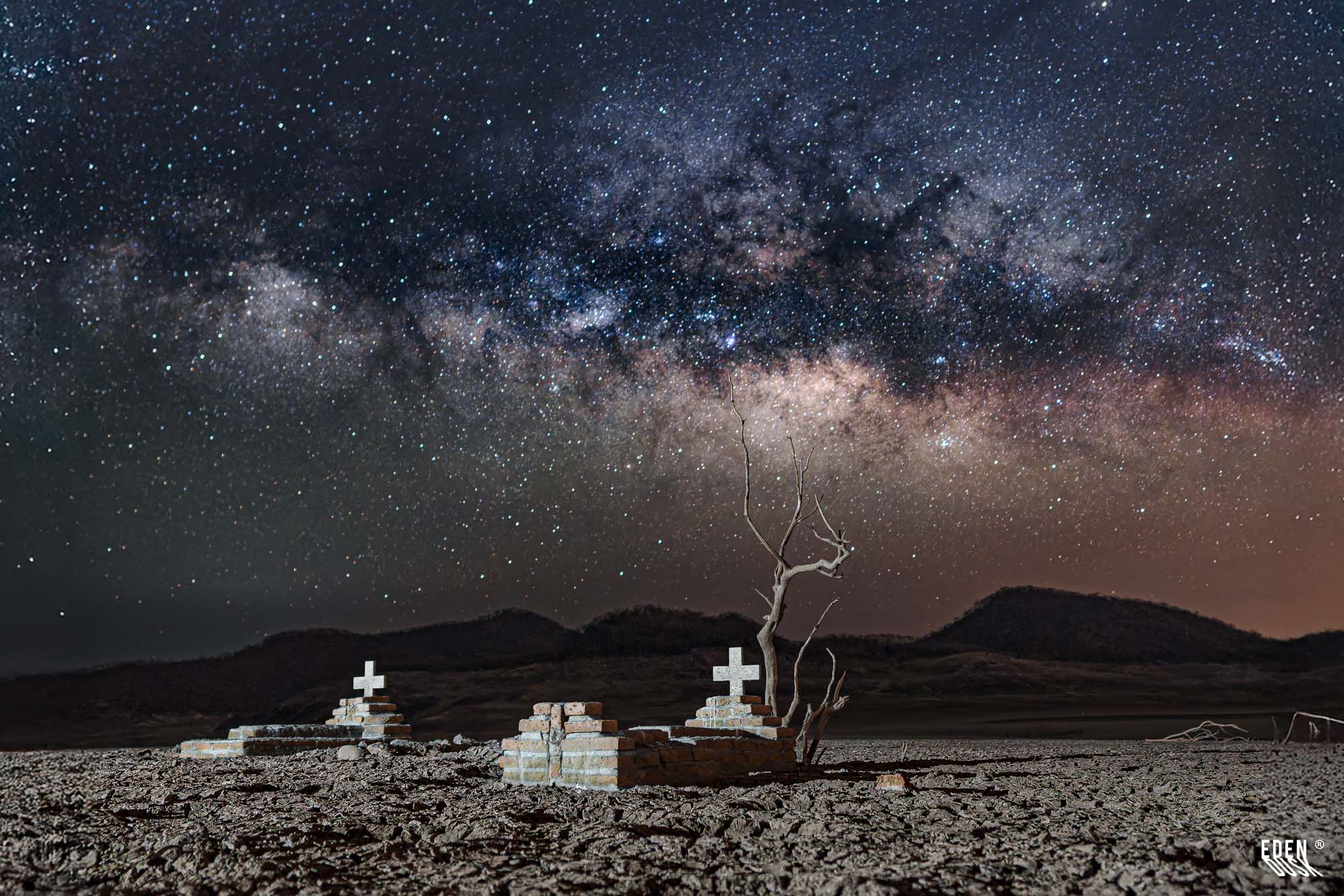 Una tumba de ladrillo y varias cruces en el Panteón de Terahuito, con el núcleo brillante de la Vía Láctea en el cielo.