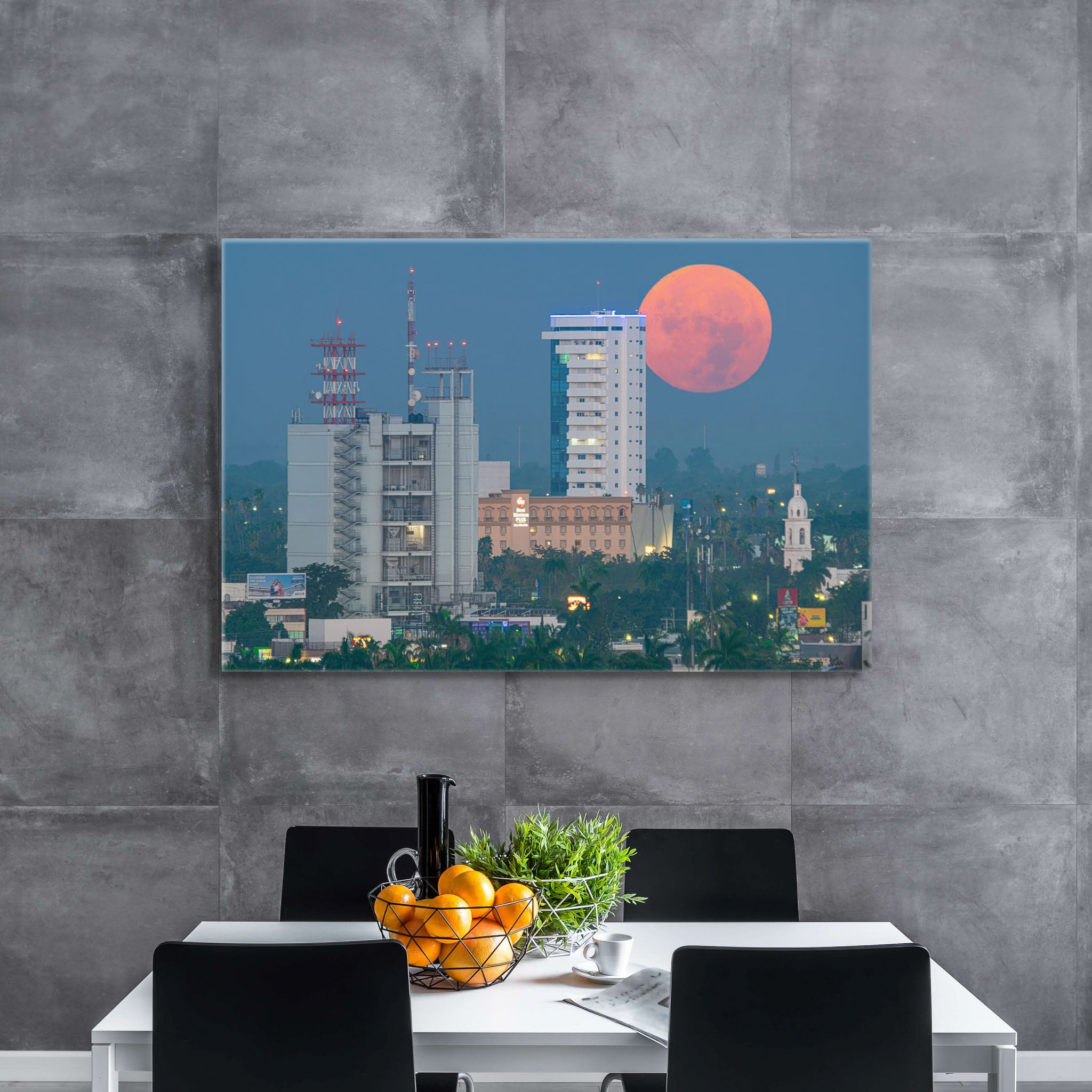 Canvas en comedor de muros grises; superluna cálida sobre perfil urbano con torres y palmeras, hora azul serena y composición limpia y equilibrada.