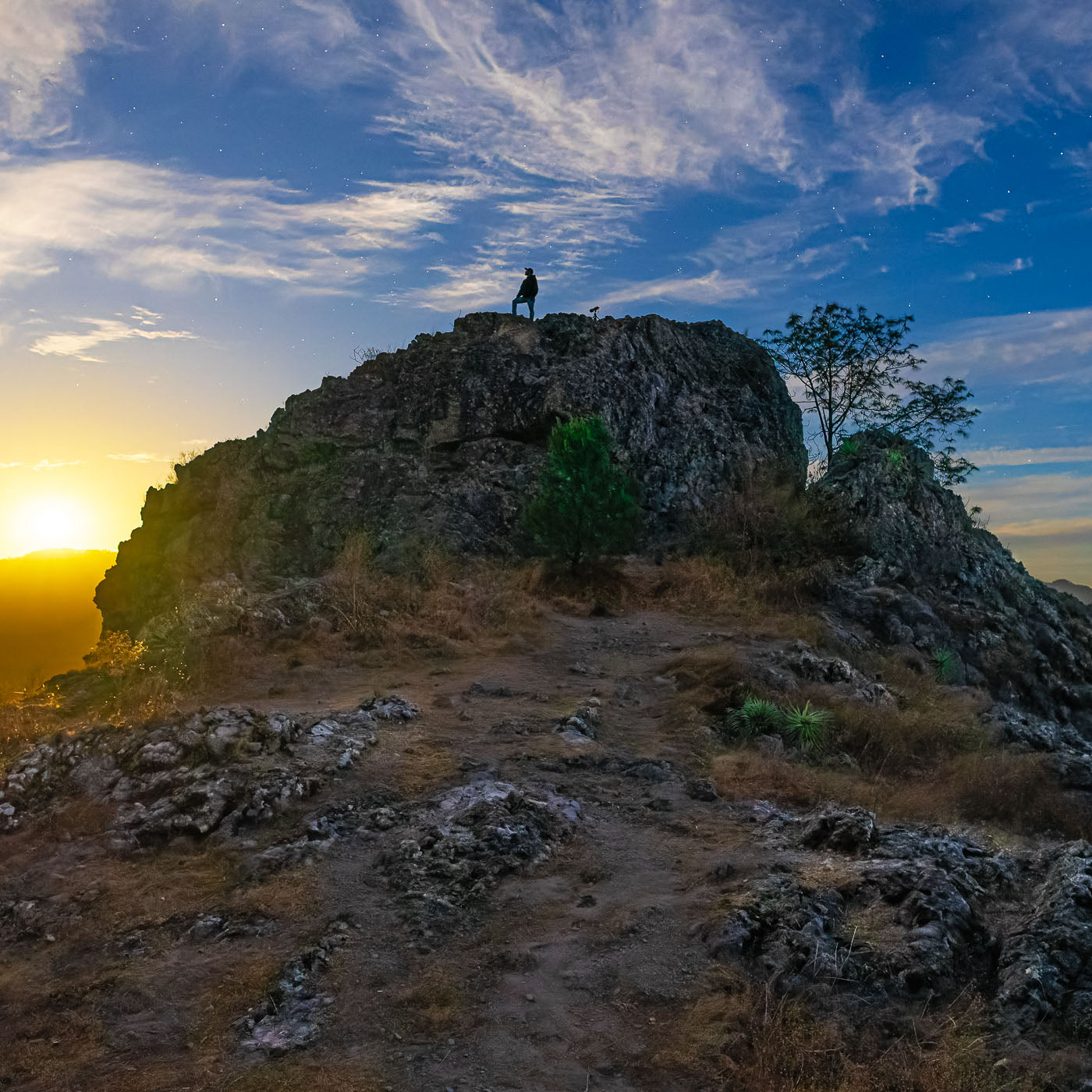 Mirador de Surutato al amanecer: figura sobre peñasco observa la sierra de Badiraguato, cielo claro.