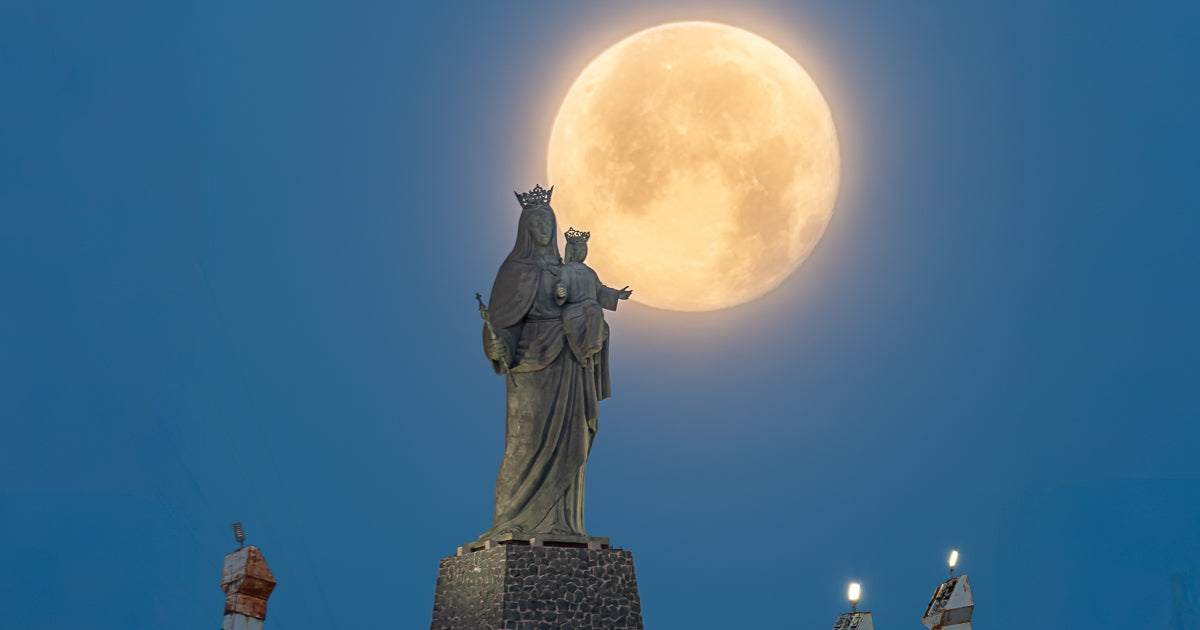 Luna llena alineada detrás de la estatua de la Virgen con el Niño en el Cerro de la Memoria, Los Mochis, al anochecer.