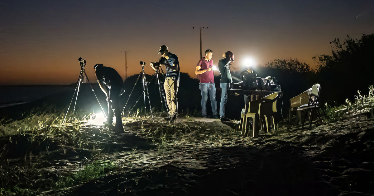 Grupo de fotógrafos con trípodes y linternas sobre dunas al anochecer, listos para una sesión nocturna en Topolobampo.