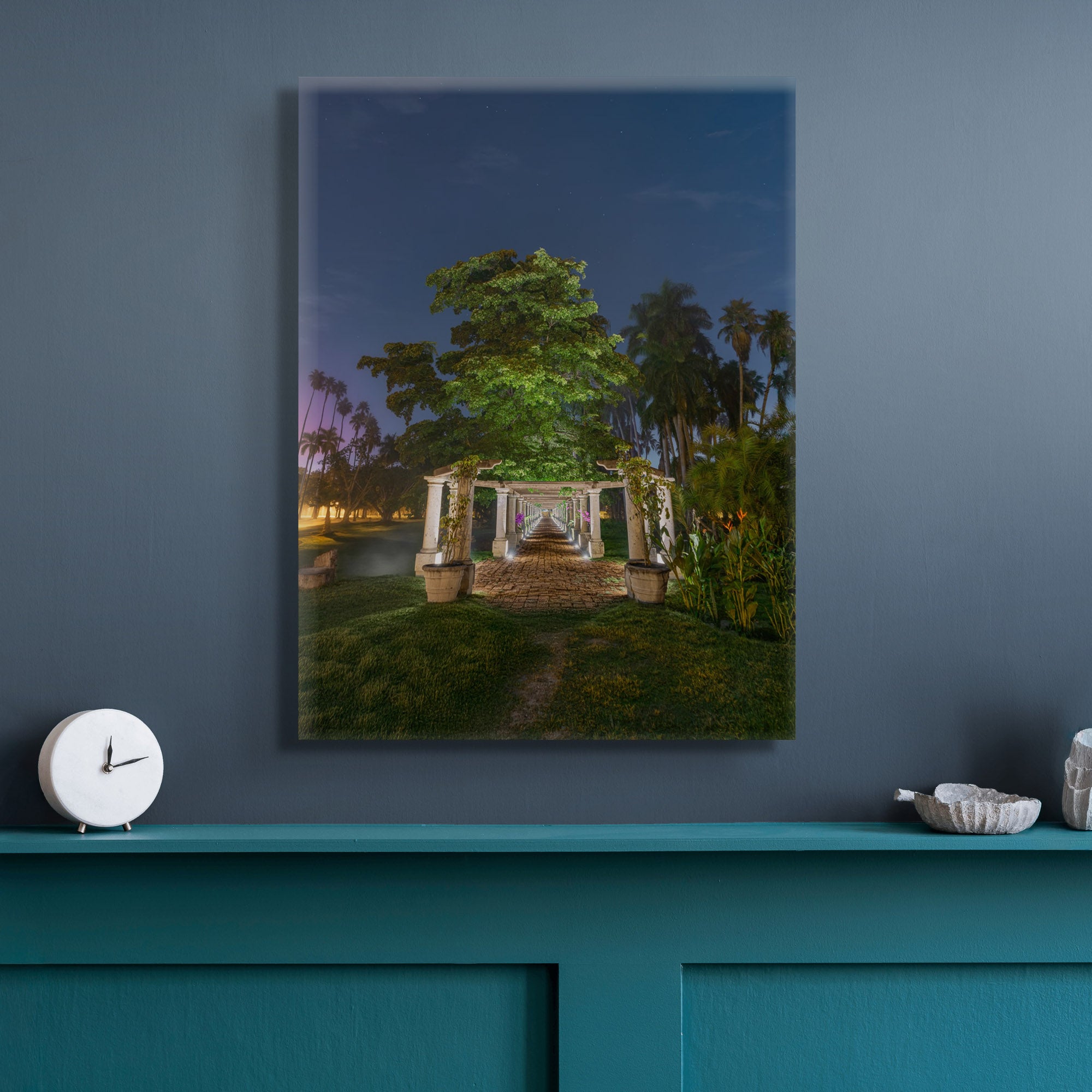 Canvas en muro gris azulado; pérgola iluminada en perspectiva central, camino de piedra y follaje nocturno; ambiente sereno y profundo.